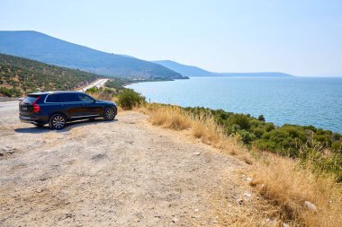 Siyah arazi aracı ve dağ ufkuyla manzaralı bir sahil manzarası. 8 Ağustos 2025 Bafa Gölü Türkiye.