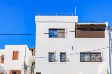 Mavi gökyüzü ve pencereleri parmaklıklı modern beyaz konut binası.