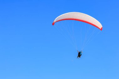 Paraglider soaring in clear blue sky adventure freedom.