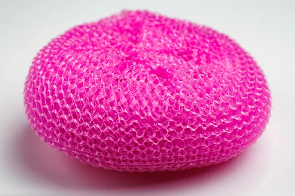 Pembe sünger beyaz arka planda duruyor. Sünger pembe ve bulanık bir dokusu var.