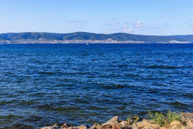 Mavi gökyüzünün altındaki uzak dağlarla Karadeniz manzarası.