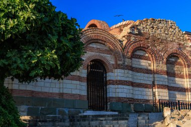 Tarih sahnesinde mavi gökyüzü ve ağaç ile antik tuğla mimarisi.