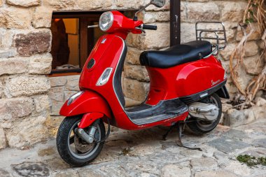 Kırsal taştan duvara park edilmiş kırmızı mobilet. 1 Ağustos 2025, Nessebar Bulgaristan.