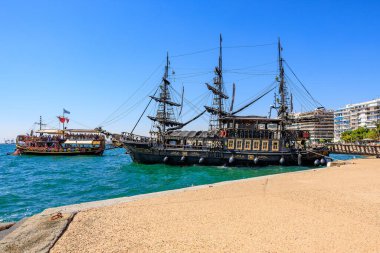 A large black ship is docked at the beach. The ship is surrounded by a group of people. August 8, 2024 Thessaloniki Greece
