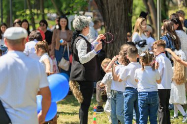 Farklı yetişkinlerin ve çocukların aktivitelere katıldığı açık hava çocuk oyunu etkinliği. 22 Mayıs 2025 Balti Moldova.