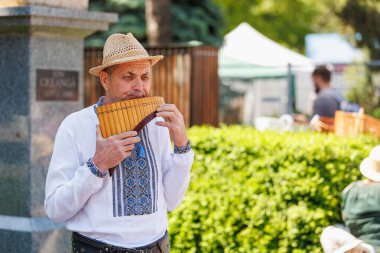 Geleneksel kıyafetlerle dışarıda pan flütü çalan yaşlı beyaz bir erkek. 22 Mayıs 2025 Balti Moldova.