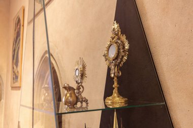 Tarihi bir ortamda cam raflarda sergilenen karmaşık altın dini eserler. 19 Mart 2025, Karlstejn, Çek Cumhuriyeti.