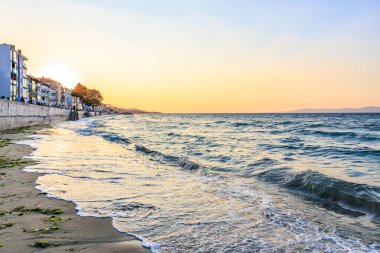 Sakin sahilde sakin bir gün batımı, dalgalar ve sahil binaları. 9 Ağustos 2025, Mudanya Türkiye.