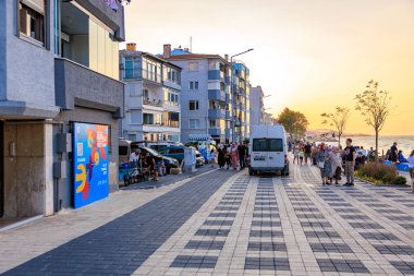 Gün batımında insanlar ve binalarla dolu bir sahil sokağı. 9 Ağustos 2025, Mudanya Türkiye.