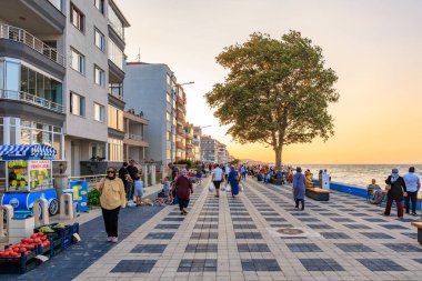 Gün batımında insanlar gezinirken canlı bir sahil gezintisi. 9 Ağustos 2025, Mudanya Türkiye.