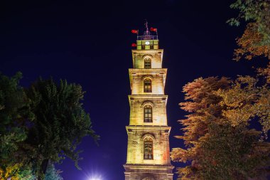 Aydınlatılmış sedirli saat kulesi Sonbahar ağaçlarının arasında.