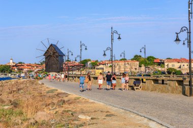 Turistler Nessebar 'da güneşli eski yel değirmeni patikalarında geziniyorlar. 1 Ağustos 2025, Nessebar Bulgaristan.