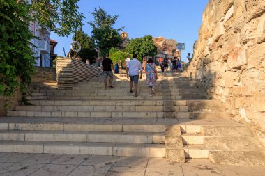 Güneşli bir günde tarihi Avrupa kasabasında taş basamaklarda yürüyen turistler. 1 Ağustos 2025, Nessebar Bulgaristan.