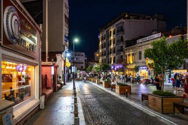 Canlı bir caddede, aydınlatılmış dükkanlar ve restoranlarla dolu bir gece hayatı. 2 Ağustos 2025, Canakkale Türkiye.