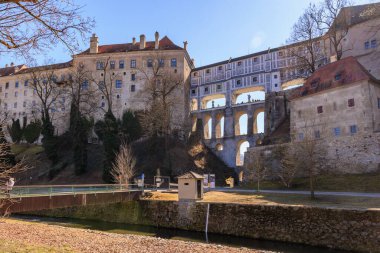 Açık mavi gökyüzünün altındaki tarihi fosforlu krumlov kalesi ve köprüsü. 20 Mart 2025, Cesky Krumlov, Çek.
