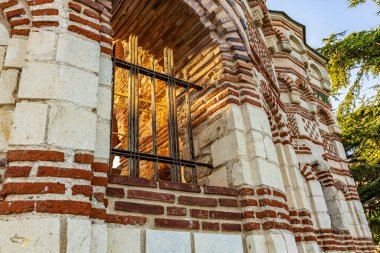 Güneş ışığında demir parmaklıkları olan tarihi tuğla ve taş mimarisi.
