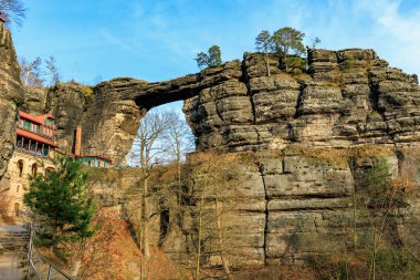Görkemli kumtaşı kemeri ve pitoresk doğal manzaradaki tarihi bina.
