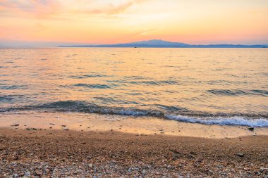 Okyanus sakin ve gökyüzü güzel turuncu bir renktir. Kumsal kayalık ve su koyu mavi.