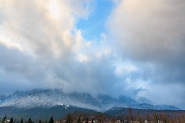 Karla kaplı dağ sırası dramatik bulutlu gökyüzünün altında.