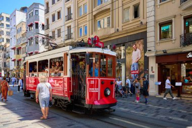 Tarihsel kırmızı tramvay yazın yayalarla dolu bir şehir caddesinde dolanıyor. 11 Ağustos 2025, İstanbul Türkiye.