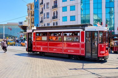 Güneşli bir günde hareketli şehir sahnesinde tarihi kırmızı tramvay. 11 Ağustos 2025, İstanbul Türkiye.