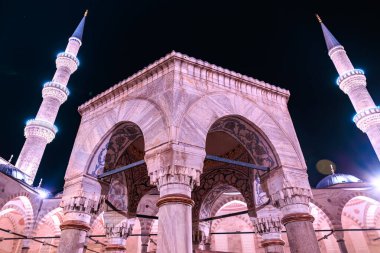 Tarihi bir cami avlusunda geceleyin aydınlatılmış Osmanlı mimarisi.