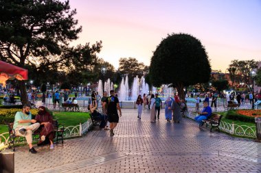 Fıskiyeler ve çeşitli kalabalıklarla dolu bir parkta akşam yürüyüşü. 11 Ağustos 2025, İstanbul Türkiye.