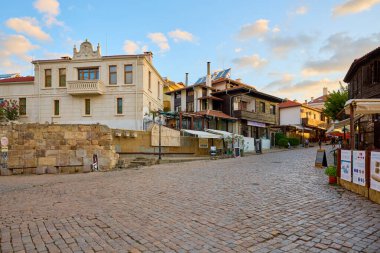 Eski şehirde gün batımında kaldırım döşemesi ve büyüleyici mimarisi olan tarihi bir sokak sahnesi. 14 Ağustos 2025, Sozopol Bulgaristan.