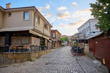 Gün batımında tuhaf bir köy ortamında, kır evlerinin olduğu, parke kaldırımlı bir cadde. 14 Ağustos 2025, Sozopol Bulgaristan.