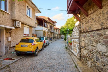 Renkli arabaları ve sakin şehir ortamında taş binaları olan hoş bir kaldırım taşı caddesi. 14 Ağustos 2025, Sozopol Bulgaristan.