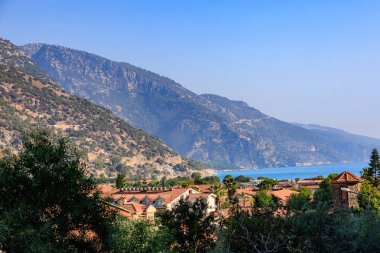 Görkemli dağların altındaki Akdeniz kıyı köyü ve berrak mavi gökyüzü.