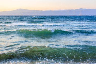 Gün batımında dalgalı dalgalı sakin sahil manzarası.