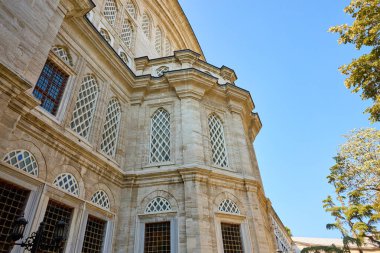 Kafes pencereli ve mavi gökyüzü arkaplanlı tarihi Osmanlı mimarisi.