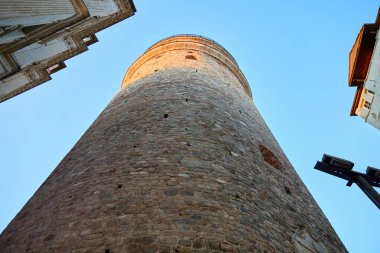 Mavi gökyüzü arkaplanlı tarihi taş kule manzarası.