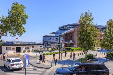 Limana yanaşmış arabaların, yayaların ve yolcu gemisinin olduğu güneşli bir sokak manzarası. 12 Ağustos 2025 İstanbul Türkiye.