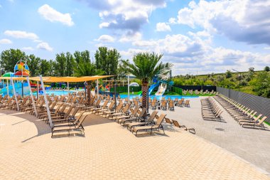 Havuzu ve bir sürü şezlongu olan bir plaj. Sandalyeler yayılmış ve havuz palmiye ağaçlarıyla çevrili. 8 Haziran 2024 Balti Moldova