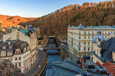 Karlovy nehri manzarası ve günbatımında tarihi binalar. 18 Mart 2025, Karlovy Vary, Çek Cumhuriyeti.
