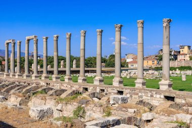 Açık mavi gökyüzünün altındaki antik taş sütunlar. İzmir, İzmir 'de antik İzmir kalıntıları.