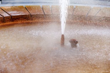 Yuvarlak taştan bir havuza su sıçrayan çeşmenin yakın çekimi, doğal gayzer..