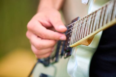 Açık havada elektro gitar çalan beyaz bir erkeğin yakın çekimi..