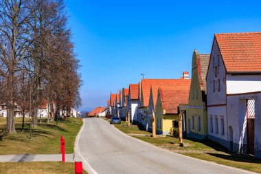 Açık havada renkli evleri olan tuhaf Avrupa köyü caddesi. 21 Mart 2025, Holasovice, Çek.