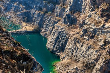 Parlak güneş ışığı altında turkuaz suyu olan görkemli kayalık taş ocağı.