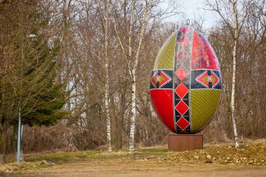 Yapraksız orman ortamında devasa geometrik desenli paskalya yumurtası heykeli. 3 Mart 2026, Suceava Romanya.