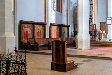 A large, empty church with a wooden pew and a wooden lectern. The church is large and has a lot of empty space. December 14, 2024 Brasov Romania