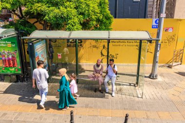 İstanbul 'daki otobüs durağı sahnesinde çeşitli insanlar ve grafiti var. 12 Ağustos 2025 İstanbul Türkiye.