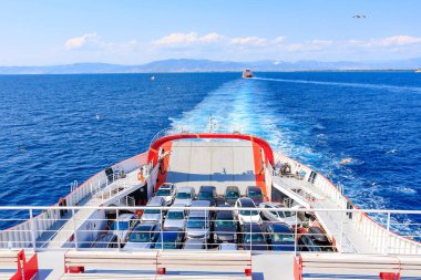 Güvertede bir sürü araba olan büyük bir kırmızı tekne okyanusta yüzüyor. 5 Ağustos 2024 Keramoti 'den Yunanistan' a feribot