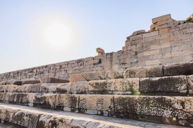 Parlak güneş ışığı altındaki antik taş amfi tiyatro tarihi mimariyi yakalıyor..