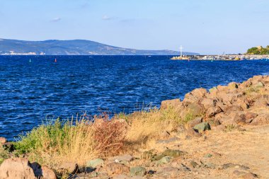 Kıyı manzarası kayalık kıyı şeridi ve berrak gökyüzü altında sakin mavi deniz.