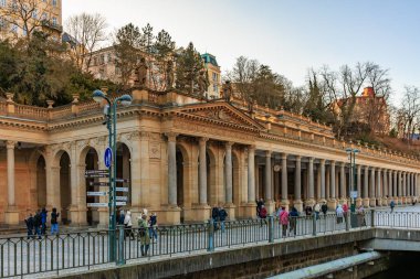 Karlovy 'deki görkemli sütunlar çeşitli ziyaretçilerle alacakaranlıkta değişir. 18 Mart 2025, Karlovy Vary, Çek Cumhuriyeti.