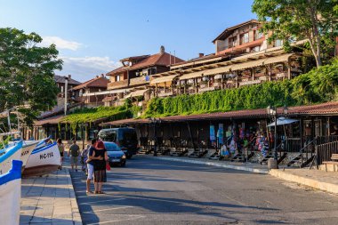 Yaz öğleden sonraları turistlerin gezdiği güneşli sahil caddesi. 1 Ağustos 2025, Nessebar Bulgaristan.